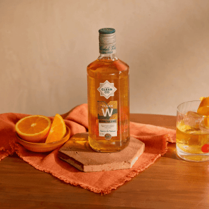 CleanCo Clean W Alcohol Free Whisky with sliced orange and glass on wooden table, smooth 0.0% whisky alternative.